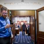 Rep. Justin Parish, D-Juneau, checks his phone before a practice session in the House of Representatives with other new legislators at the Capitol on Friday, Jan. 13, 2017.