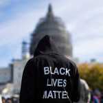 In this Oct. 10, 2015 photo, a man wears a hoodie which reads, "Black Lives Matter" on the lawn of the Capitol building in Washington during a rally to mark the 20th anniversary of the Million Man March.