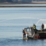 Steve Hamilton watches as members of the U.S. Coast Guard, Capital City Fire/Rescue and harbor department put out a fire on the tugboat Consul D outside of Aurora Harbor on Monday.