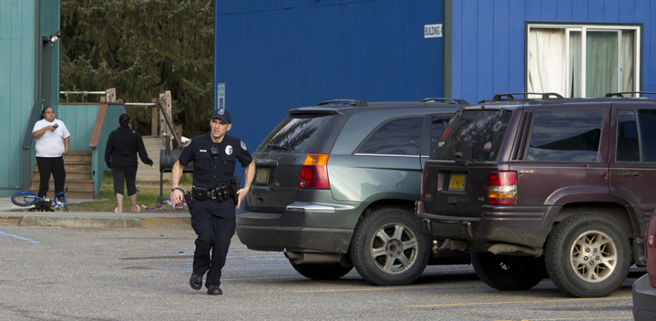 A Juneau Police Department officer runs after being told that a person jumped out an open window, right, and ran into the woods at the Coho Park Apartments on Friday. Police were at the apartment complex investigating the shooting of a 19-year-old woman.