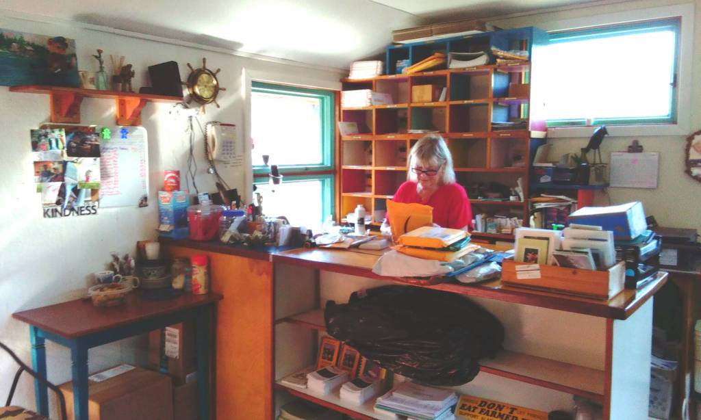 Meyers Chuck post mistress Cassie Peavey sorts and scans the mail. On a table to the left of the counter shes put a bowl of homemade cookies for anyone who helped haul the mail up to the post office. (Tara Neilson | For the Capital City Weekly)