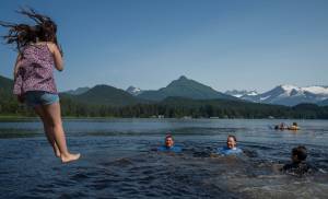 Eunavae Smallwood, 9, follows her father, Wayne, and brothers, Landon, 11, and Lakai, 13, into Auke Lake on Monday, July 23, 2018. Wayne said, We come every day, even if its raining. It just feels great. (Michael Penn | Juneau Empire)