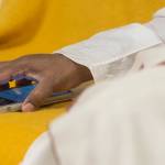 Spiritual leader Sri Sri Ravi Shankar of The Art of Living Foundation checks his cell phone during an interview at Juneau-Douglas High School on Tuesday, July 31, 2018, before leading a group meditation in the JDHS auditorium. (Michael Penn | Juneau Empire)