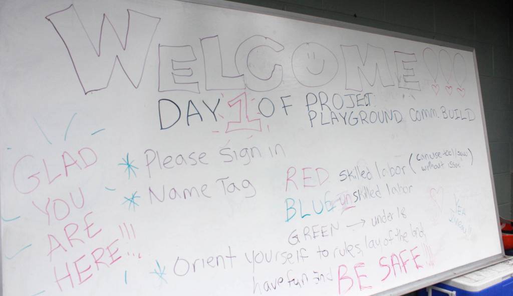 Words on a whiteboard welcome volunteers to the first day of the Project Playground community build on Aug. 8, 2018. (Alex McCarthy | Juneau Empire)
