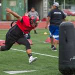 Marcos Yadao, of Juneau-Douglas High School, works on a footwork and tackling drill run by his father, Vince, during Juneau Football practice at Thunder Mountain High School on Thursday, July 26, 2018. (Michael Penn | Juneau Empire File)