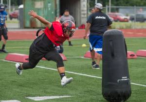 Marcos Yadao, of Juneau-Douglas High School, works on a footwork and tackling drill run by his father, Vince, during Juneau Football practice at Thunder Mountain High School on Thursday, July 26, 2018. (Michael Penn | Juneau Empire File)
