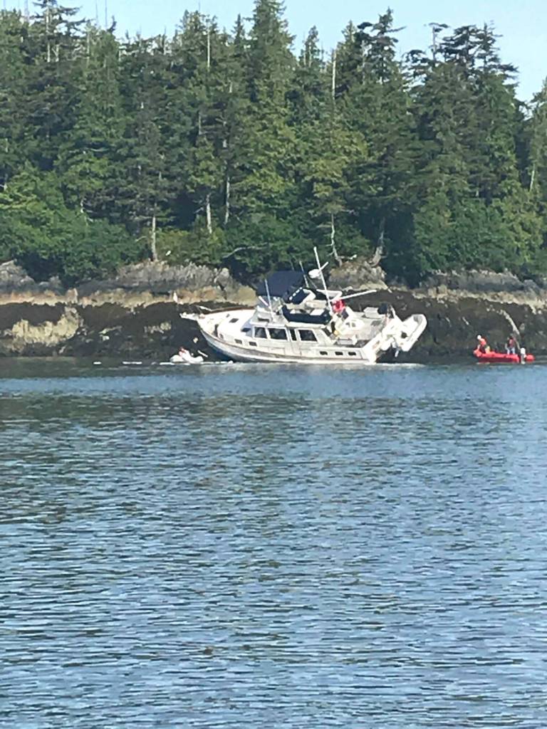Tourists inspect their aground boat as the tide retreats, hoping its undamaged. (Robin Neilson | For the Capital City Weekly)