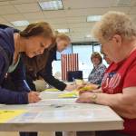 Retired preschool teacher Katy Harman, left, is the first person to vote Tuesday morning, Aug. 21, 2018 at the Douglas Public Library during the 2018 Alaska Primary Election. (James Brooks | Juneau Empire)