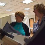 Election volunteers at the Douglas Public Library set up the touch-screen voting machine before the polls open Tuesday morning, Aug. 21, 2018. (James Brooks | Juneau Empire)