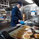 Chef Berkeley Scott, of the buoy tender Hickory, prepares two burgers to be judged on Thursday, Aug. 23, 2018. (Michael Penn | Juneau Empire)