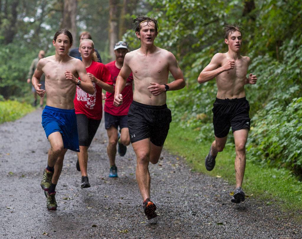 Ambrose Bucy, left, Sadie Tuckwood, Clem Taylor-Roth, center, and Koby Goldstein run with ultra-marathon runner Geoff Roes, hat, during Juneau-Douglas High School cross country practice at Sandy Beach at the Treadwell Historic Mining Area on Tuesday. (Michael Penn | Juneau Empire)