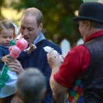 Britain's Prince William, the Duke of Cambridge, holds Princess Charlotte, as she is given a balloon animal during a children's tea party at Government House in Victoria, British Columbia, Thursday