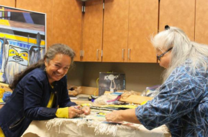 In this file photo from August, Clarissa Rizal, left, and Della Cheney, right, work on the "Weavers Across the Water" robe.