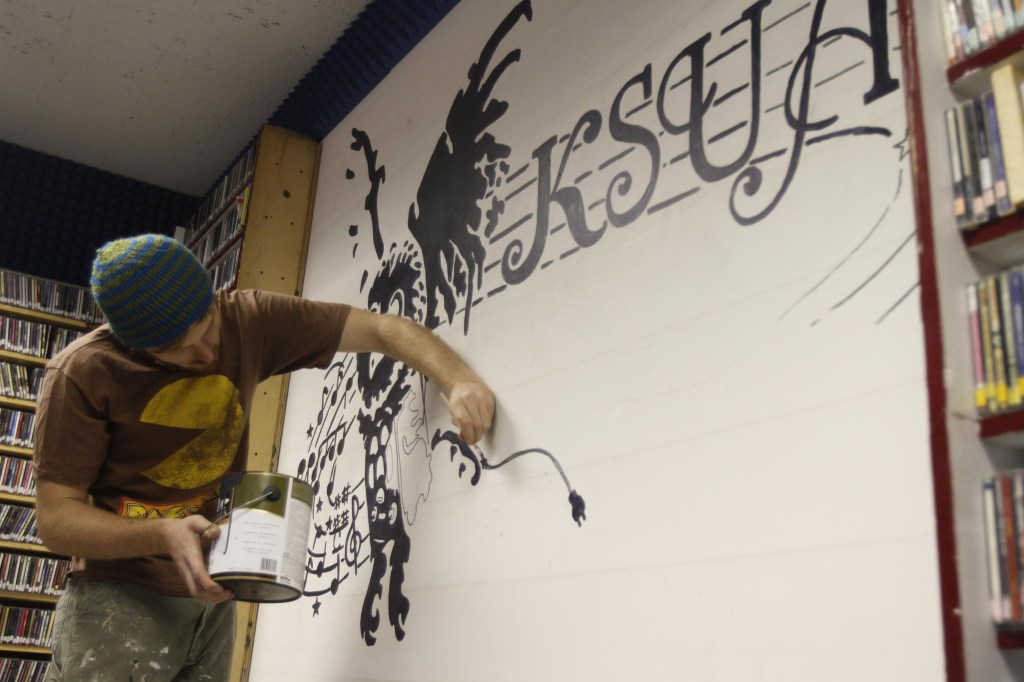 James Kelly paints KSUA&rsquo;s wall mual. Photo by Annie Bartholomew.