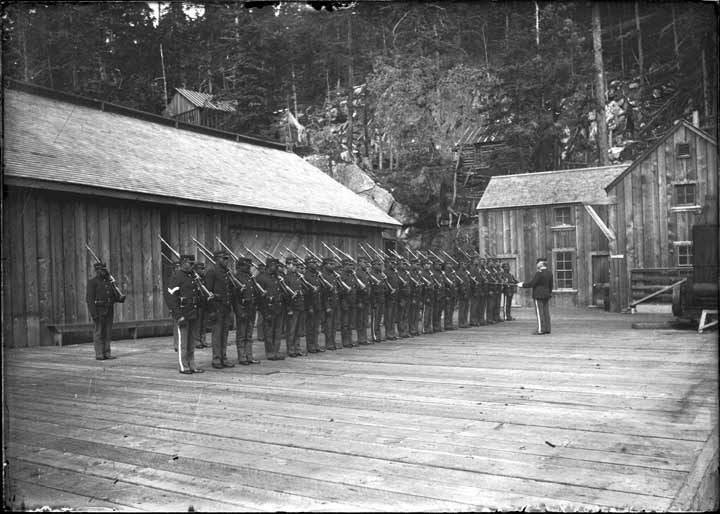 African-American soldiers stand at attention on the Klondike Company&rsquo;s wharf in Dyea. Note from Karl Gurcke: They were (in Dyea) for a brief period of time (July 1899) before they were burned out by a forest fire and had to move to Skagway. Photo courtesy of the Alaska State Library - Historical Collections.