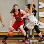 Juneau-Douglas High School junior Cassie Dzinich (21) dribbles the ball around Ketchikan High School senior Kyra Welker (44) on Friday during the Crimson Bears&rsquo; 56-39 win against the Lady Kings. (Taylor Balkom | Ketchikan Daily News)