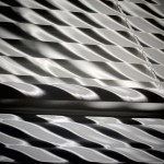 Sunlight comes through a set of Venetian blinds on the south wall and shining on another set of Venetian blinds on the west wall of the room. Photo by Ray Tsang.