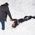 Eli Wharton, 16, is helped up by his friend Joseph Sypeck, 16, after being filmed diving into a pile of snow behind the downtown Bullwinkle&rsquo;s Pizza Parlor on Thursday. (Michael Penn | Juneau Empire)