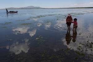 In this Feb. 2 photo, cousins from the Avila family search for discarded toys on the shores of Lake Titicaca, in Coata in the Puno region of Peru.The shores of South America&rsquo;s largest lake are littered with dead frogs, discarded paint buckets and bags of soggy trash. Less visible threats lurk in the water itself: highly toxic levels of lead and mercury. (Rodrigo Abd | The Associated Press)