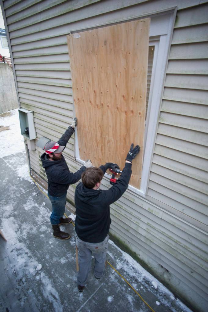 Austin Henderson, left, and Sky Martin, of Carver Construction, board up windows after the city closed the Bergmann Hotel for health and safety reasons on Friday. (Michael Penn | Juneau Empire)
