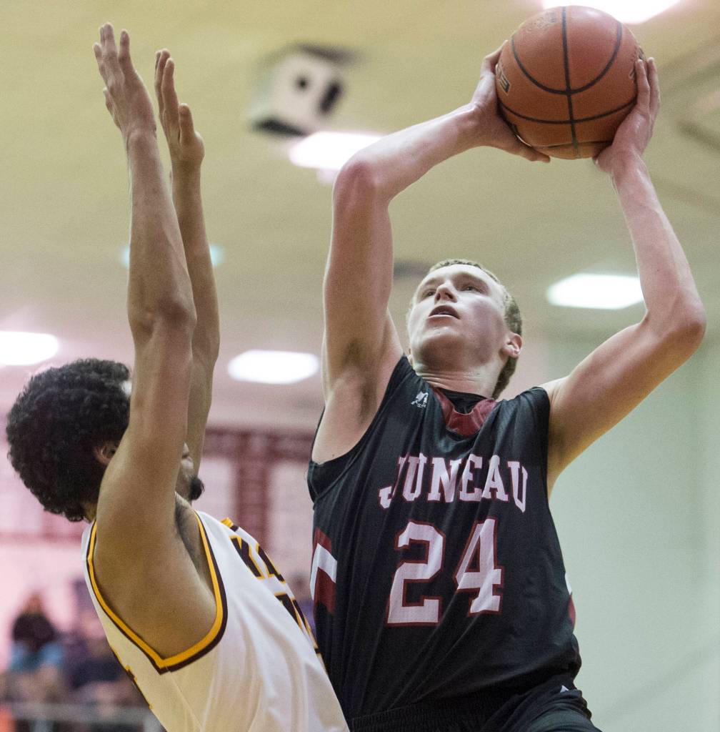 Juneau-Douglas&rsquo; Erik Kelly shoots against Ketchikan&rsquo;s Shakim Bauer during the Region V Basketball finals at JDHS on Friday. (Michael Penn | Juneau Empire)