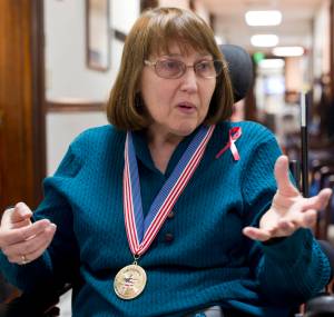 Susan Macaulay, an Air Force Veteran from Juneau, speaks with Rep. Justin Parish, D-Juneau, at the Capitol on Wednesday. Macaulay is wearing her National Disabled Veterans Winter Sports Clinic&rsquo;s 30th Anniverary medal. (Michael Penn | Juneau Empire)