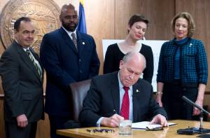 Gov. Bill Walker signs SB 91 in front of Sen. Donald Olson, D-Golovin, left, Sen. David Wilson, R-Wasilla, Rep. Ivy Spohnholz, D-Anchorage, and Sen. Cathy Giessel, R-Anchorage, in his Capitol conference room on Tuesday, March 21, 2017. The bill authorizes the chief medical officer of the Department of Health and Social Services to issue a standing order for the prescription of an opioid overdose drug. (Michael Penn | Juneau Empire)