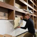 Jake Lapenter works under new walnut shelving at the new bar called The Narrows on Thursday. The bar opens to the public on Monday. (Michael Penn | Juneau Empire)