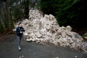 Alex Tolbert walks next to an avalanche that reached Judy Lane on Friday, March 31, 2017. (Michael Penn | Juneau Empire)