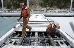 Jeff Trucano, left, and Sam Miller, of Trucano Construction, work at installing lighting fixtures on the new dock in Douglas Harbor on Jan. 4. (Michael Penn | Juneau Empire File)