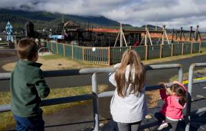 Sibblings Marco Carranza, 5, left, Monica, 11, center, and Kaitlyn, 3, view Project Playground from behind police tape on Tuesday. A fire set by two 13-year-old boys destroyed the playground Monday. (Michael Penn | Juneau Empire)