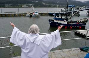 Pastor Suellen Bahleda, of Resurrection Lutheran Church, blesses the fishing vessel Trinity to start the Blessing of the Fleet and Dedication of Names at the Alaska Commercial Fishermen&rsquo;s Memorial in Juneau on Saturday, May 7, 2016. (Michael Penn | Juneau Empire file)