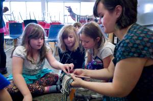 In this file photo from June 2015, instructor Lily Hope helps Maisy Messing, left, with ravenstail weaving as Sofia Lindoff, center, and Zoie Branch watch during their Juneau Fine Arts Camp class at Juneau-Douglas High School. (Michael Penn | Juneau Empire File)