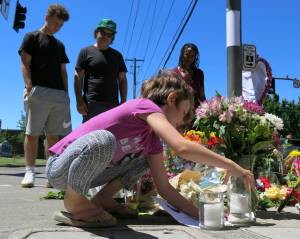 Coco Douglas, 8, leaves a handmade sign and rocks she painted at a memorial in Portland, Oregon on Saturday, May 27, 2017, for two bystanders who were stabbed to death Friday while trying to stop a man who was yelling anti-Muslim slurs and acting aggressively toward two young women. From left are Coco&rsquo;s brother, Desmond Douglas; her father, Christopher Douglas; and her stepmother, Angel Sauls. (Gillian Flaccus | The Associated Press)
