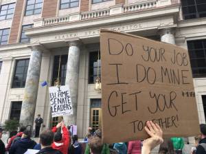 Protesters hold signs during the AFL-CIO rally in front of the Alaska Capitol on Sunday. Participants chanted for the Alaska Legislature to pass and fund a state budget.  James Brooks |  Juneau Empire