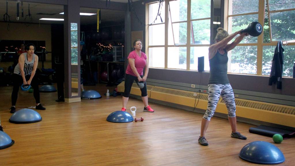 Students in the HIIT (High Intensity Interval Training) class at Mountainside Wellness strengthen threir core muscles during a kettlebell exercise Monday afternoon. (Erin Granger | Juneau Empire)