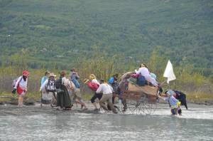 Latter-day Saint youth ford a river during a reenactment of a pioneer trek, pulling wooden handcarts up the Knik River Valley. (Photo courtesy of Mark Stauffer)