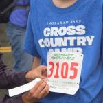 A race volunteer removes a runner&rsquo;s bib stub at the finish line of the Glenn Frick Memorial Mile. (Nolin Ainsworth | Juneau Empire)