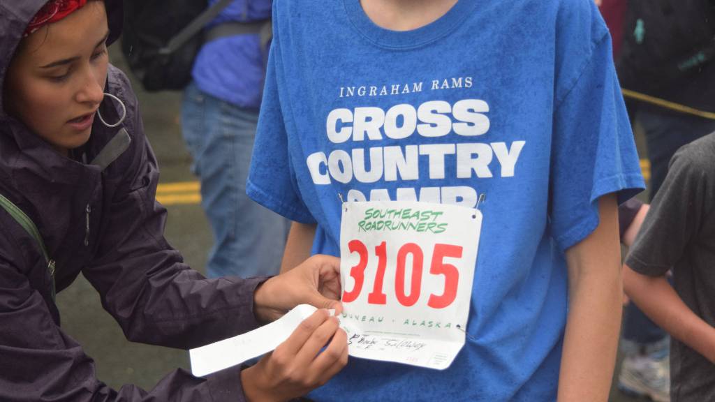 A race volunteer removes a runner&rsquo;s bib stub at the finish line of the Glenn Frick Memorial Mile. (Nolin Ainsworth | Juneau Empire)