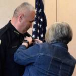 Juneau Police Department Chief Ed Mercer has his badge pinned on him by his wife, Kelly, at his swearing-in Monday. (Liz Kellar | Juneau Empire)