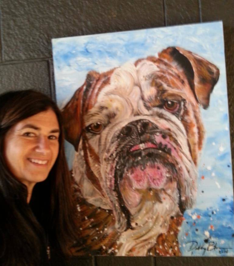 Debby Bloom poses by a portrait she painted of a dog. Bloom paints portraits of pets on commission. Courtesy image.
