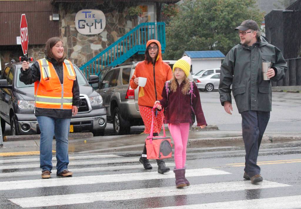 Crossing Guard Krista Arvidson helps Clint Farr and Denise Koch and their daughter Siena Farr cross the street to Harborview Elementary School on the first day of school Wednesday. (Alex McCarthy | Juneau Empire)