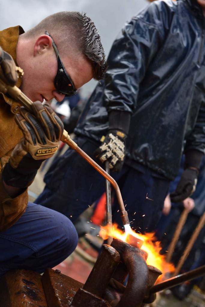 A Coast Guard Cutter Sycamore crewmember heats a rivet pin during the heat-and-beat competition, where teams use torches and hammers to seal shackles for time, during the Buoy Tender Roundup Olympics at Coast Guard Station Juneau on Wednesday, Aug. 16, 2017. This year&rsquo;s roundup included eight U.S. Coast Guard and Canadian buoy tenders, stationed throughout Alaska and the Pacific Northwest. (Petty Officer 1st Class Jon-Paul Rios | U.S. Coast Guard)