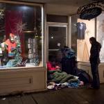 In this March 25 photo, Chloe Abbott checks in with a homeless person camping in a business doorway on South Franklin Street. (Michael Penn | Juneau Empire File)