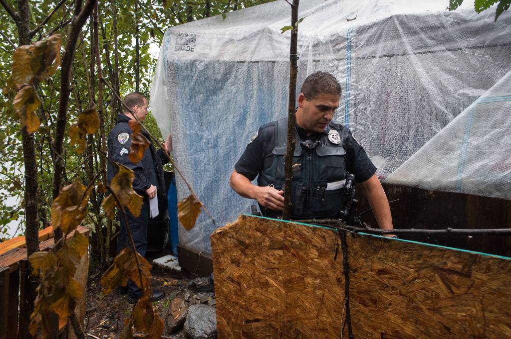 Juneau Police Department Sgt. Krag Campbell, left, and Officer Ken Colon serve eviction notices on homeless encampments as Alaska Mental Health Trust Authority employees look on on Tuesday, Aug. 22, 2017. (Michael Penn | Juneau Empire)