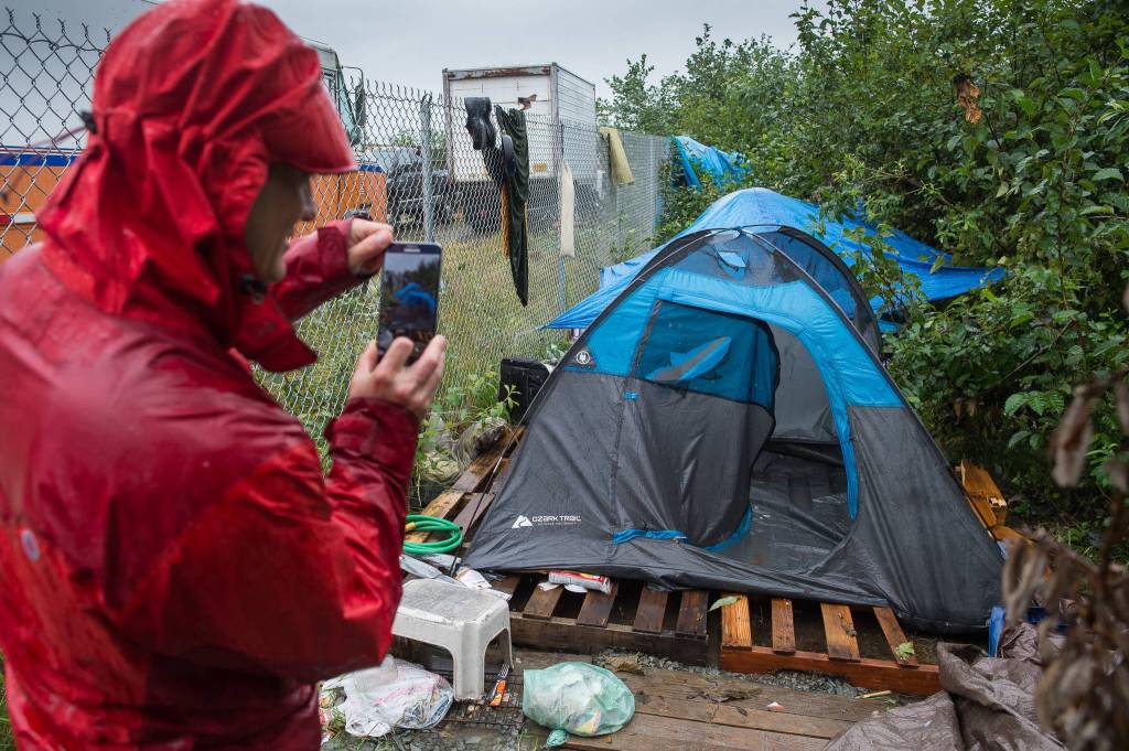 Aaron O&rsquo;Quinn, of the Alaska Mental Health Trust Authority, takes a picture as Juneau Police Department Officers serve eviction notices on homeless encampments on Tuesday, Aug. 22, 2017. (Michael Penn | Juneau Empire)