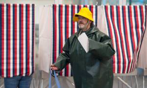 Mike Jones exits a voting booth in full rain gear after walking to the Mendenhall Valley Public Library to vote in the Municipal election on Tuesday, Oct. 3, 2017. (Michael Penn | Juneau Empire)