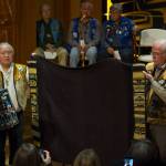 Ozzie Sheakley, left, and Gordon Greenwald hold up a blanket with strips of Chilkat weaving, one of three cultural items being transfered from the University of Pennsylvania back to the T&rsquo;akdeintan clan in Hoonah, during a ceremony at the Walter Soboleff Center on Wednesday, Oct. 11, 2017. (Michael Penn | Juneau Empire)