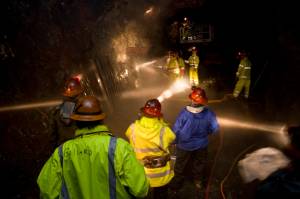 Employees of the Alaska Department of Labor and Workforce Development watch mining students in the Entry Level Underground Mining Training program learn how to hand drill in the AJ Mine in June 2010. (Michael Penn | Juneau Empire)