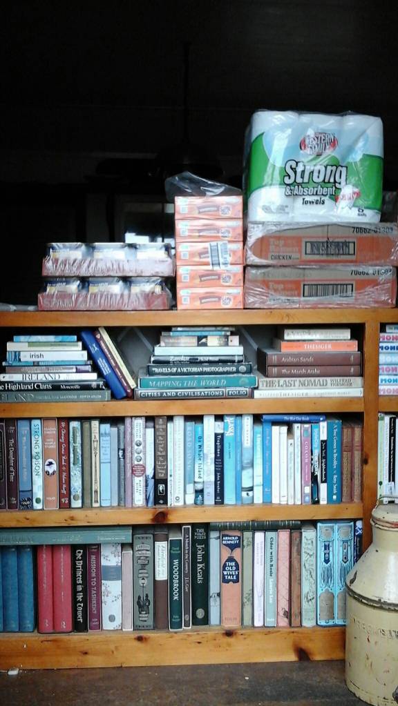 Cases of supplies stacked on a bookcase as groceries are hauled in after a fall stock-up run across the strait. Photo by Tara Neilson.